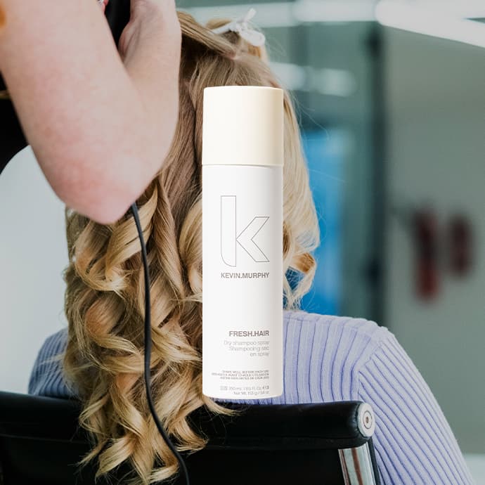 Person with curled blonde hair and white hair product